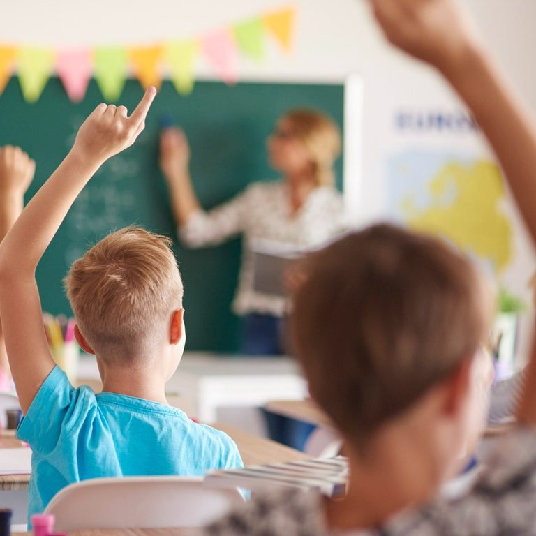 Uczniowie zgłaszają się do odpowiedzi w klasie przed zieloną tablicą
